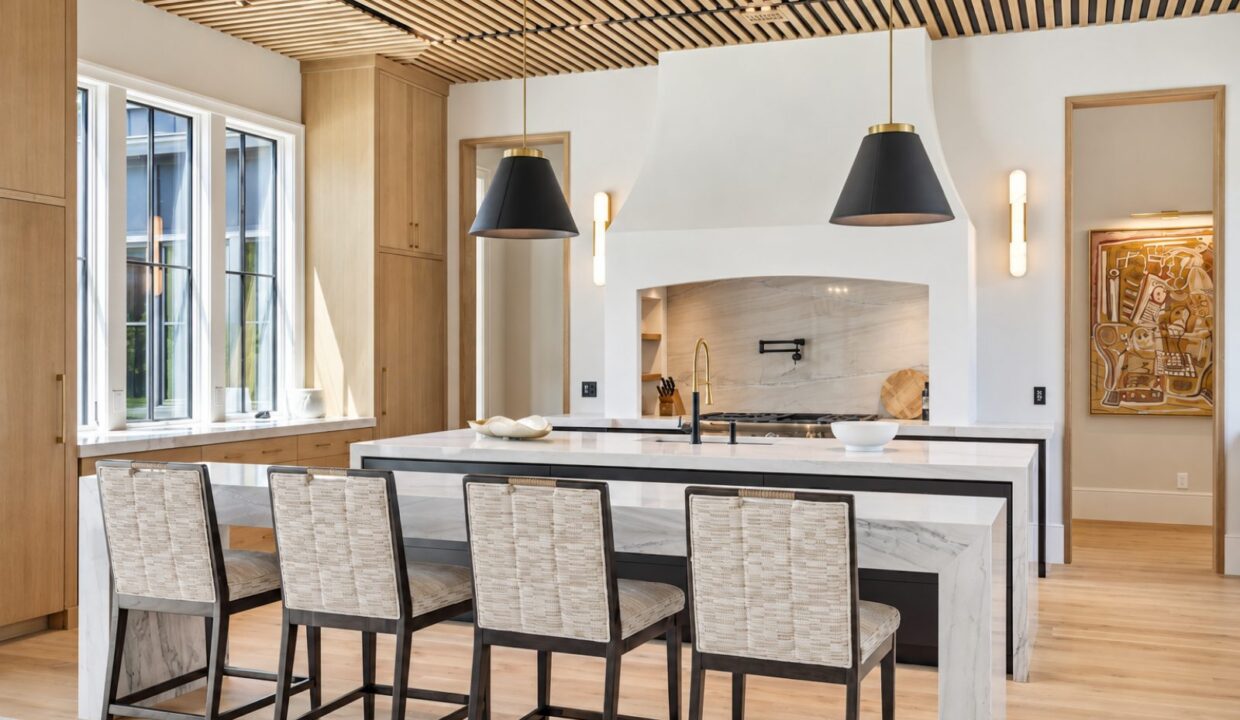 Bright kitchen with a wood-slat ceiling, black pendant lights and a white island with counter stools