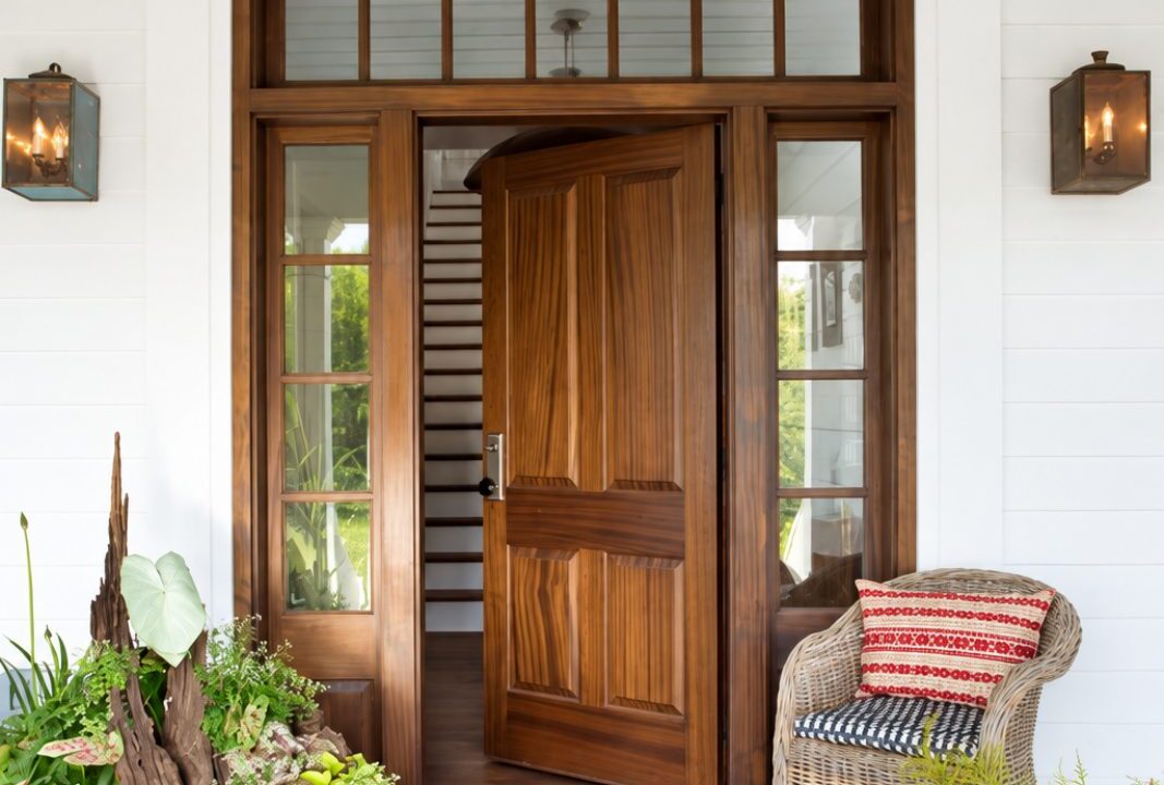 Welcoming wood front door with lantern lights and tropical plants at a Lowcountry home